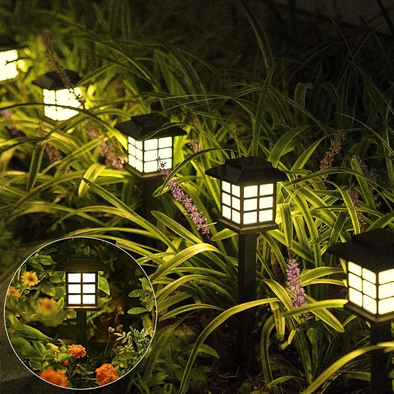 Two solar pathway lights illuminating a garden walkway at dusk