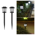 Two solar pathway lights illuminating a garden walkway at dusk